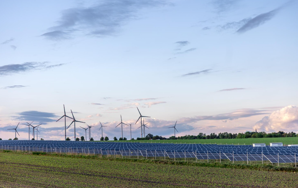 Solar panels and wind turbines in a rural field, showcasing clean energy infrastructure by climate tech startups