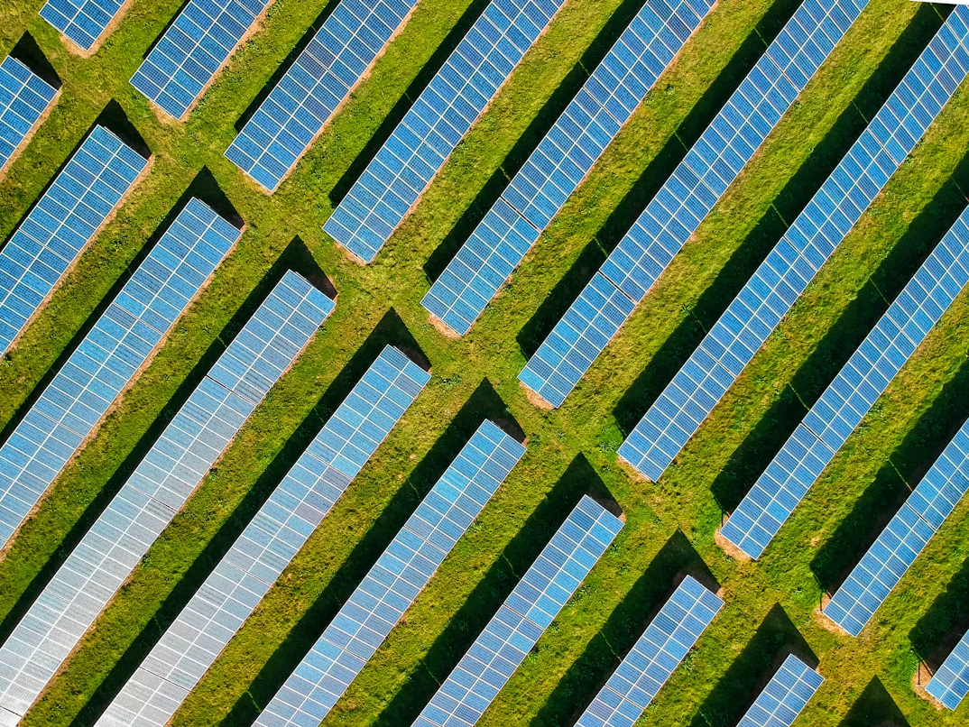 Aerial view of large solar farm showcasing global renewable energy trends with rows of blue panels on green fields