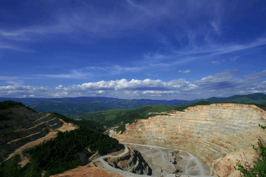 Wide view of terraced rare earth open pit mine in mountainous region showing global minerals extraction.