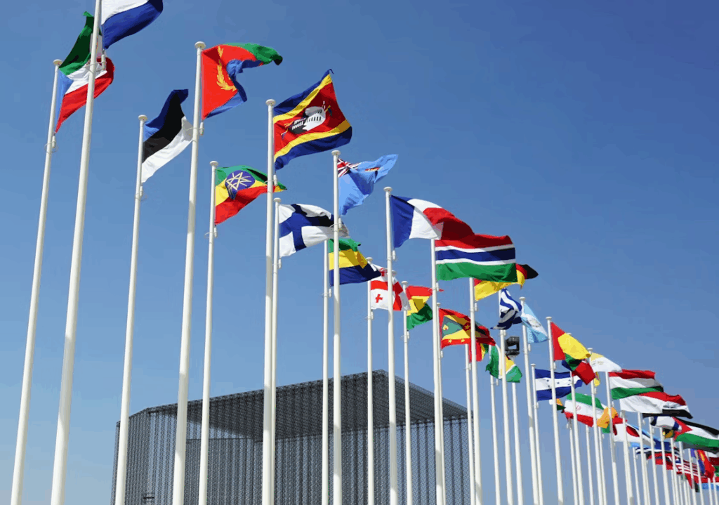 Row of international flags waving, symbolizing global diplomacy and world leaders working together.